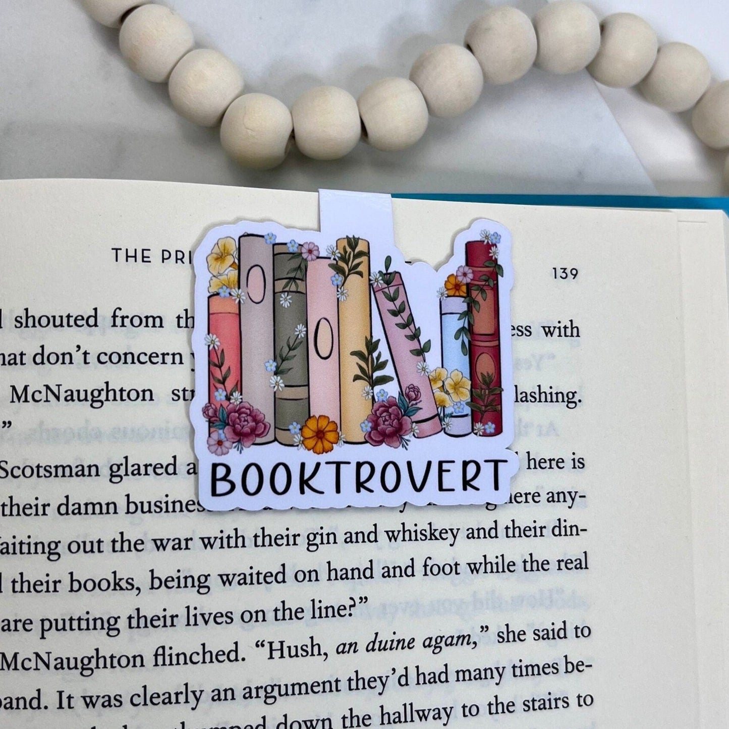 Magnetic bookmark with the text 'Booktrovert' and an illustration of books on a shelf, capturing a cozy, bookish theme